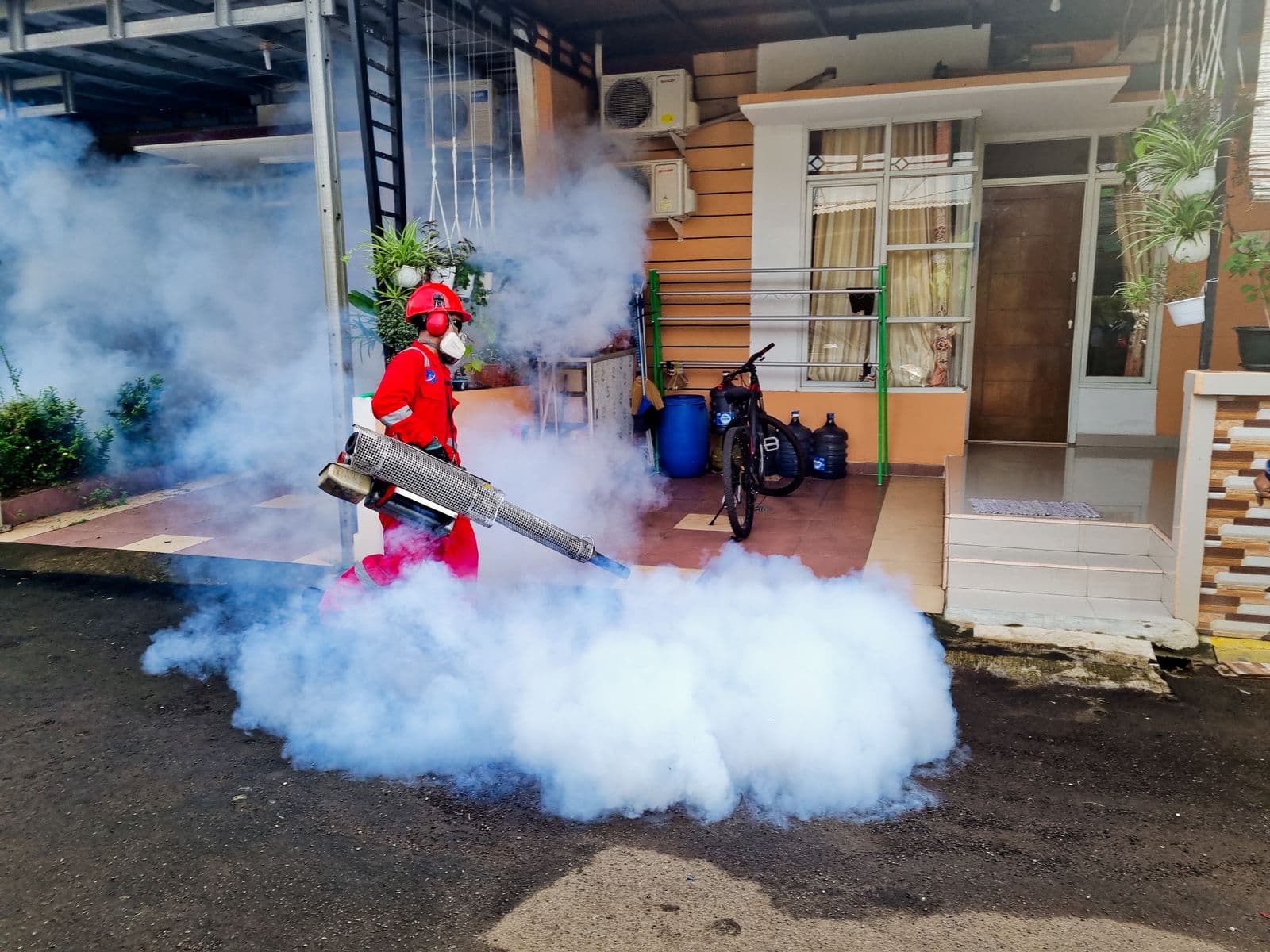 Pest control specialist treating the outside of a home