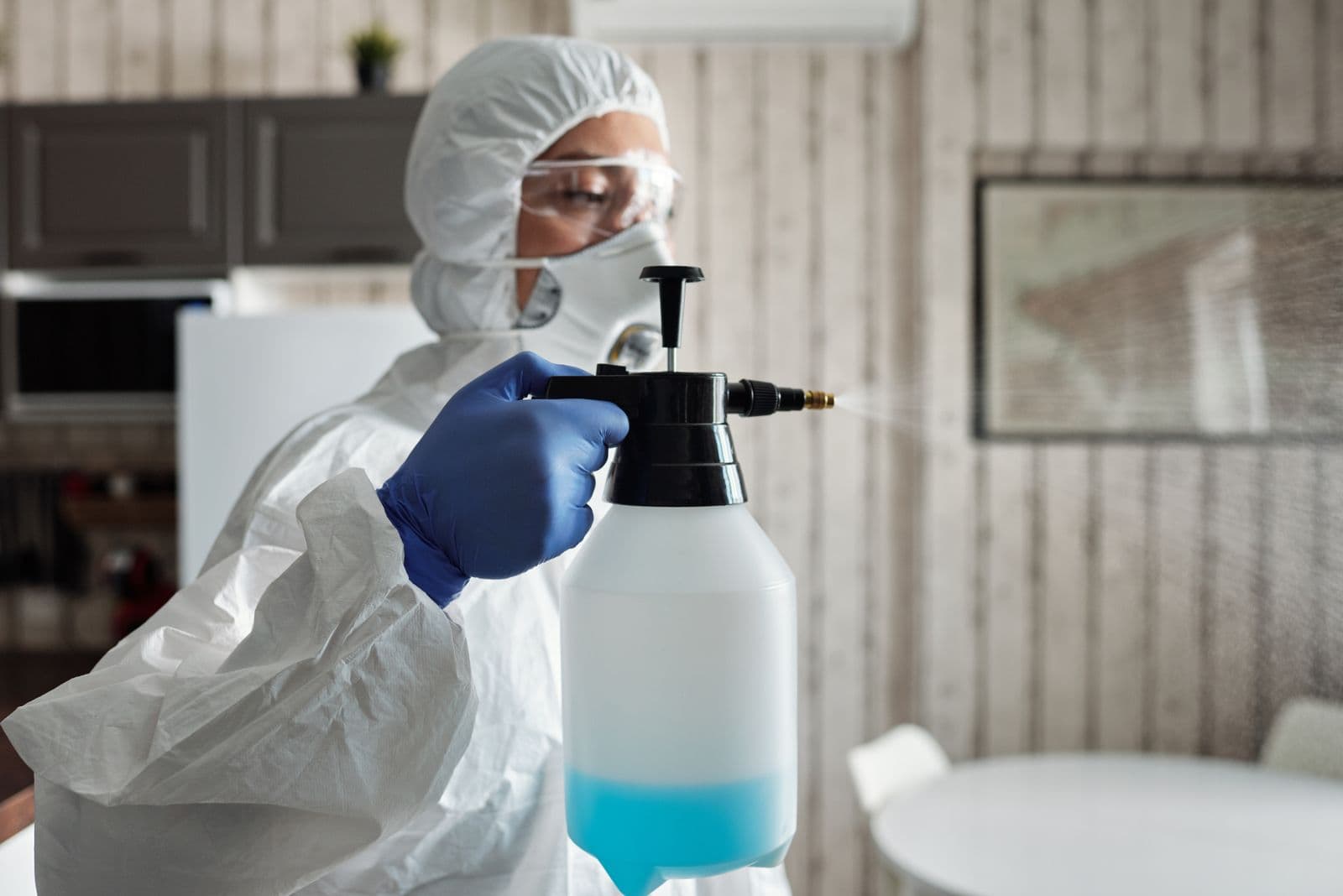 Pest control technician using a handheld sprayer indoors
